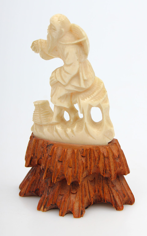 Bone figurine on the wood base 