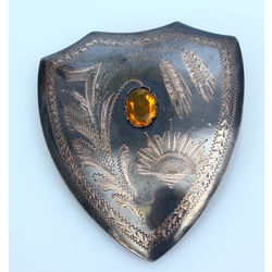 Silver brooch with yellow stone in the shape of a shield