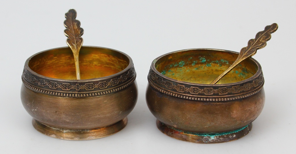 Two metal spice dishes with two silver spoons