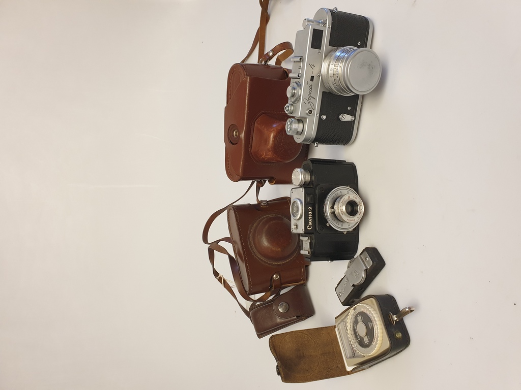 2 фотоаппарата в кожаном чехле и экспонометр
