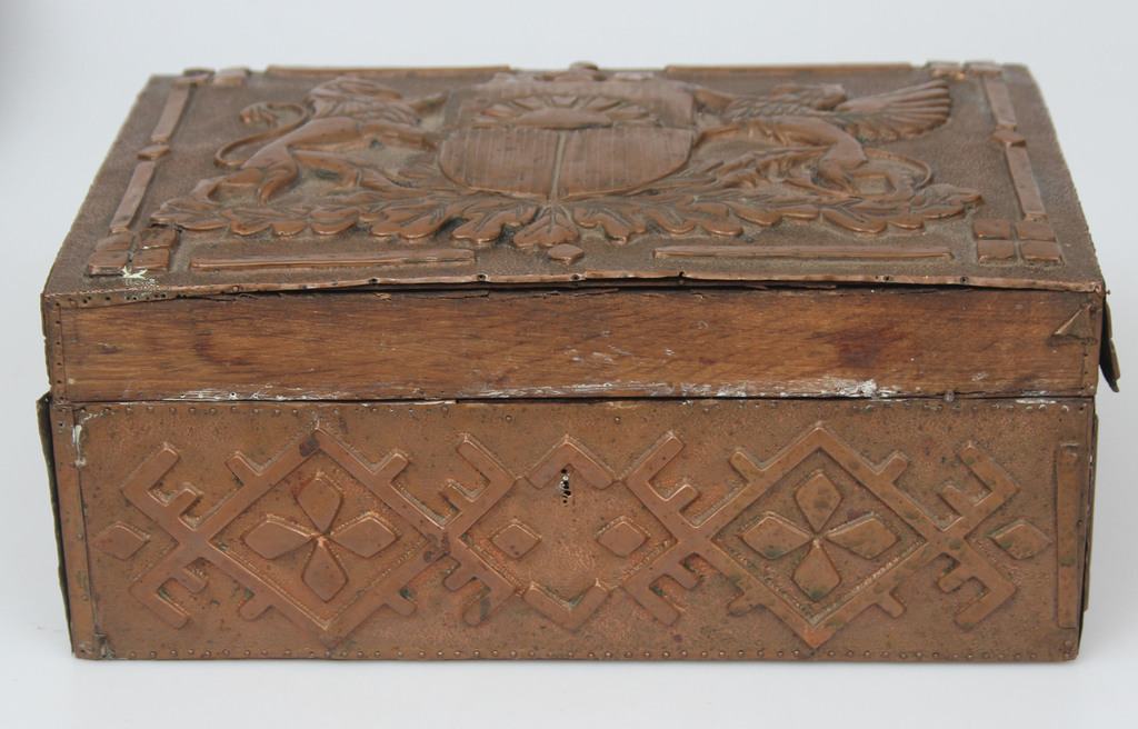 A wooden chest with a copper finish with the coat of arms of Latvia