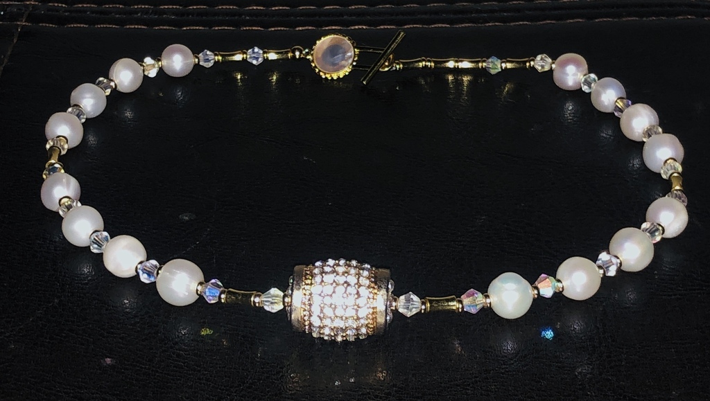 Necklace with freshwater pearls, crystals and other gold-plated elements.