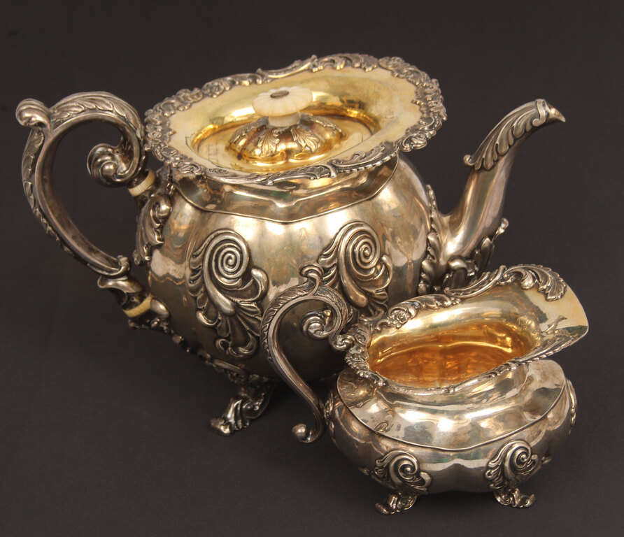 A silver teapot and creamer with gilding