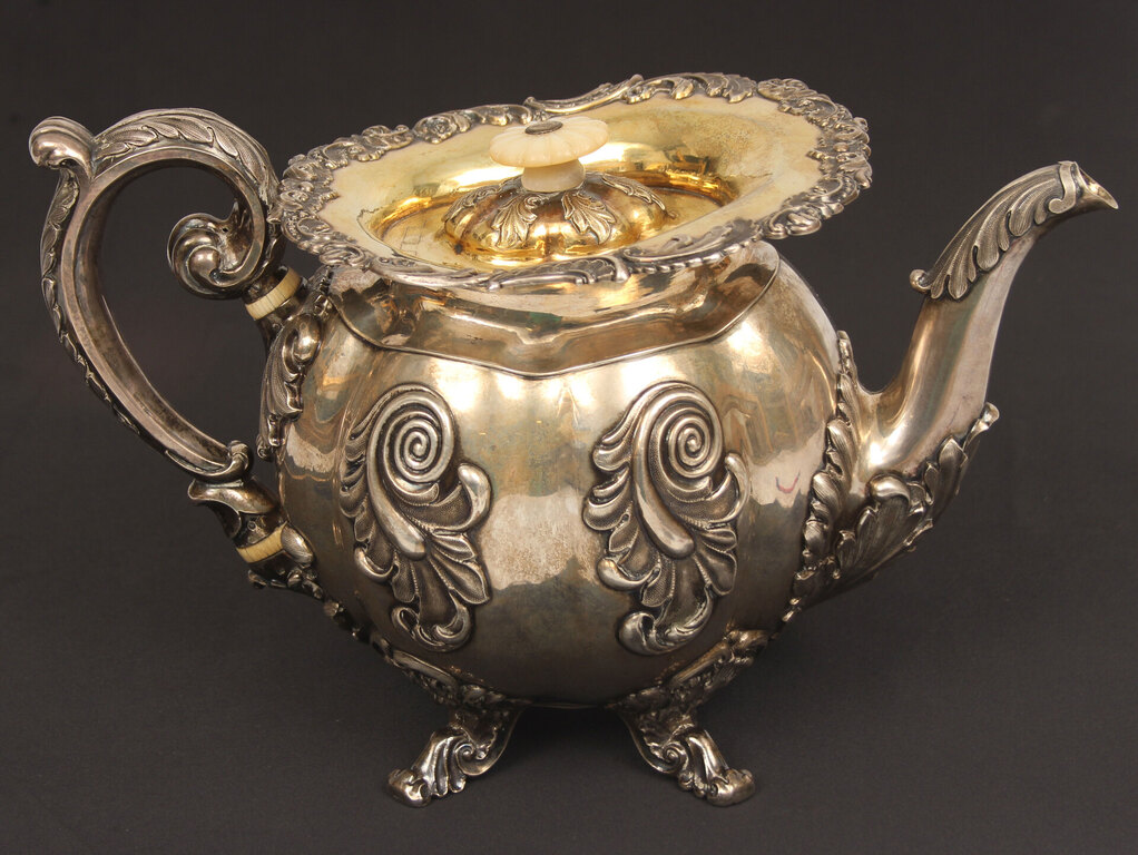 A silver teapot and creamer with gilding