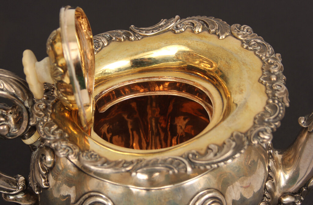 A silver teapot and creamer with gilding