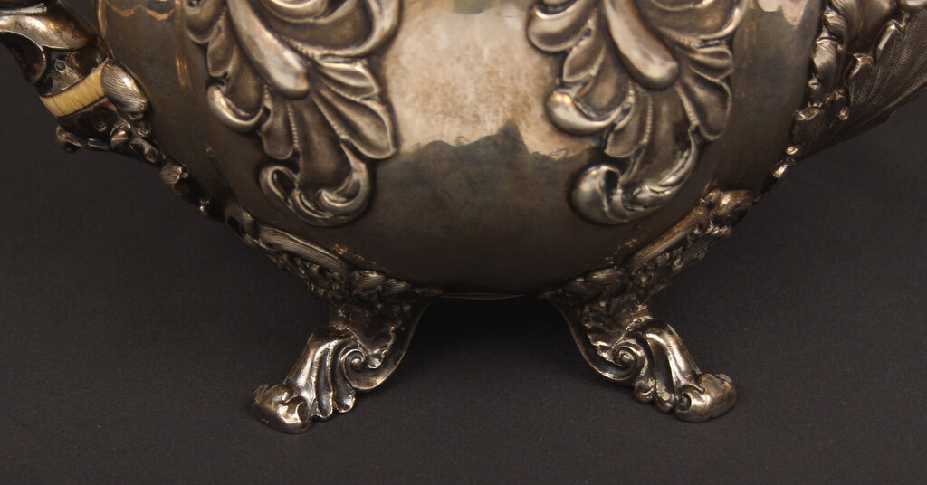 A silver teapot and creamer with gilding