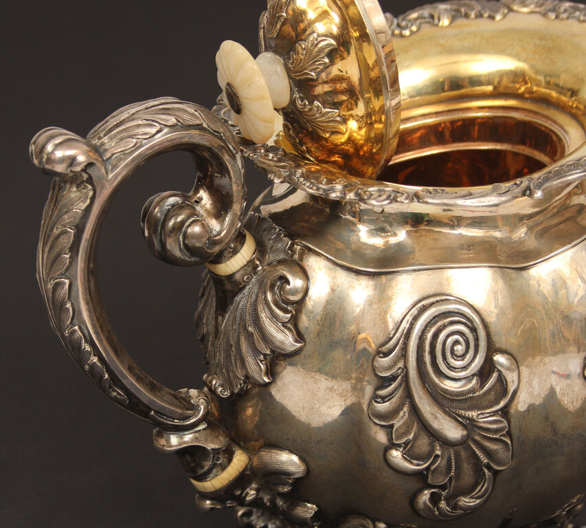 A silver teapot and creamer with gilding