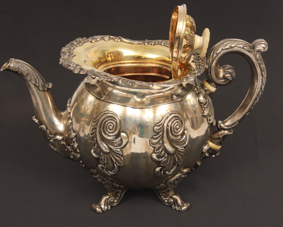 A silver teapot and creamer with gilding