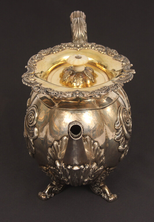 A silver teapot and creamer with gilding