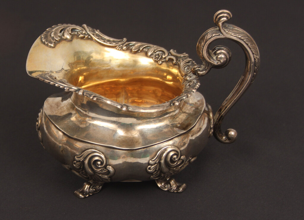 A silver teapot and creamer with gilding