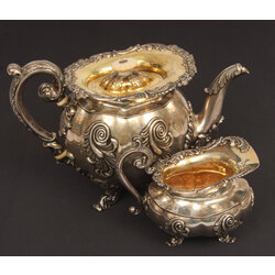 A silver teapot and creamer with gilding